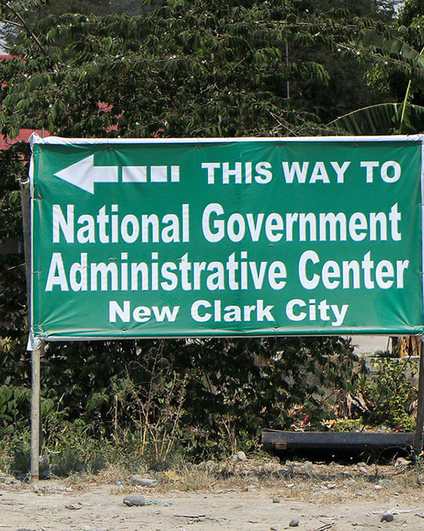 Signage pointing towards the site of New Clark City stands on the national highway near a residential area in Capas, Tarlac.