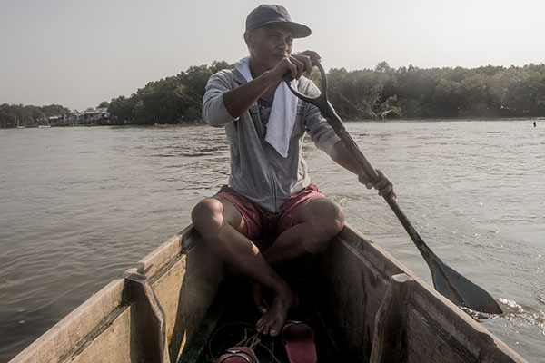 Rodel Alvarez, paddles a small boat across the narrow part of the Manila bay, where there used to be fishponds.