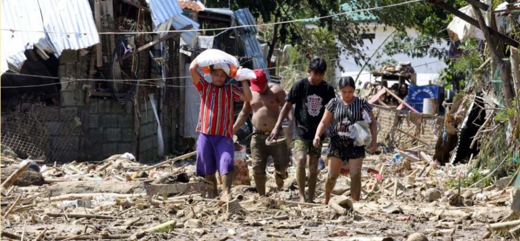 Residents walked through mud in November 2020 following the onslaught of Typhoon Ulysses (Vamco),  which triggered massive flooding.