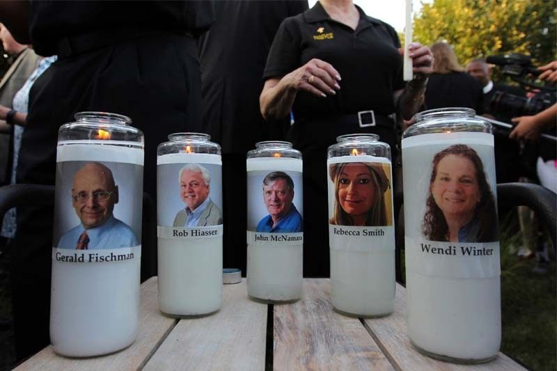 Photos of five journalists adorn candles during a vigil across the street from where they were slain in their newsroom in Annapolis, Md., Friday, June 29, 2018. Prosecutors say Jarrod W. Ramos opened fire Thursday in the Capital Gazette newsroom.