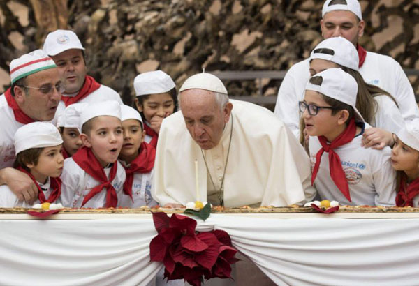 Pope Francis blows out birthday candle on extra-long pizza