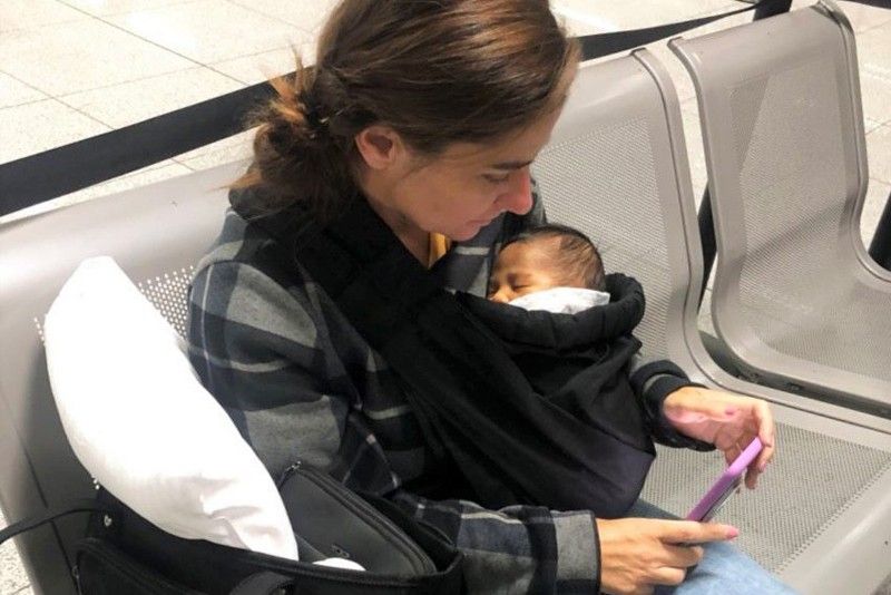 American with baby in belt bag held at NAIA