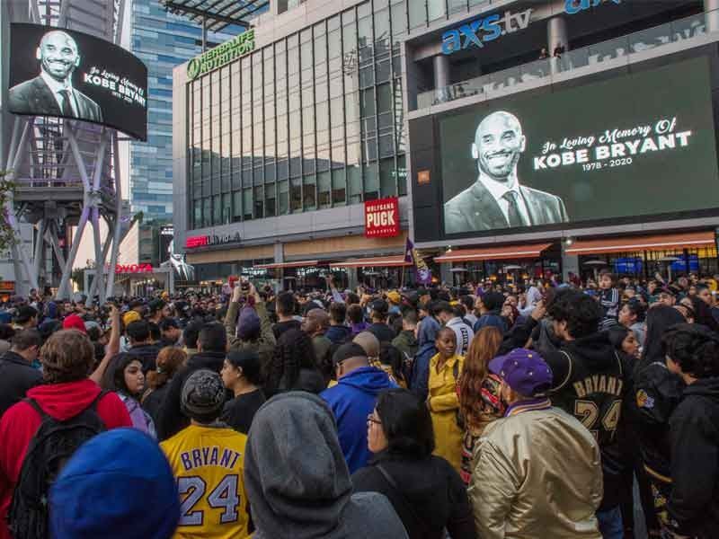People gather around a makeshift memorial for former NBA and Los Angeles Lakers player Kobe Bryant after learning of his death, at LA Live plaza in front of Staples Center in Los Angeles on January 26, 2020.