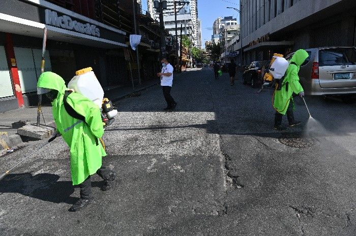 City workers wearing protective suits disinfect a street
