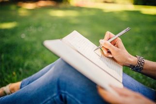 A stock photo of a person writing on a notebook.