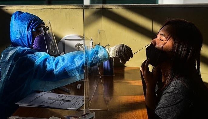 A health worker collects a swab sample from a passenger to test for the Covid-19 coronavirus, at a train station in Quezon City, suburban Manila on January 18, 2022