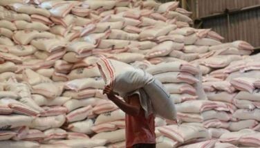 Undated photo of a person carrying a sack of rice. 
