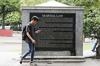 A student passes a portion of the Martial Law Memorial Wall at Mehan Garden in Manila on September 20, 2019. Engraved in a series of marble structures are the names of those who suffered and died at the height of Ferdinand Marcos&acirc;�� martial law regime from 1972 to 1986.