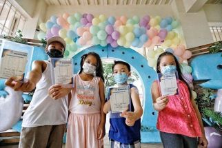 Children show their vaccination cards after getting inoculated against COVID-19 at the Marikina Sports Center on April 21, 2022.