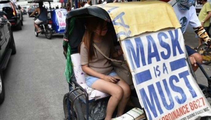 A passenger (C) sits inside a tricycle covered with a reminder to wear a mask, part of the Covid-19 health protocols, in Manila on February 16, 2022.