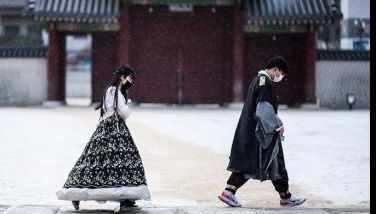 Visitors wear traditional hanbok dress as they walk on the grounds of the Gyeongbokgung Palace after snowfall in Seoul on Jan. 17, 2022.
