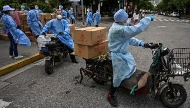 Workers ride scooters with boxes of food to be delivered to a neighborhood under a Covid-19 coronavirus lockdown in the Jing'an district of Shanghai on May 25, 2022.