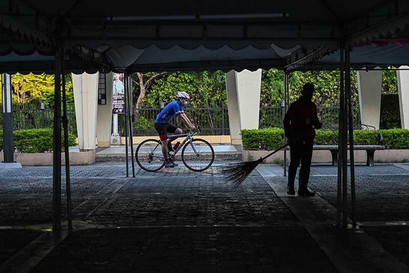 A cyclist passes by a sweeper during an event celebrating World Bicycle Day, in Quezon City, suburban Manila on June 3, 2022.