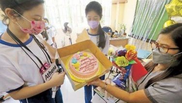 A teacher at Rafael Palma Elementary School in Manila receives flowers and a cake from her students yesterday to mark World Teachers&acirc;�� Day.