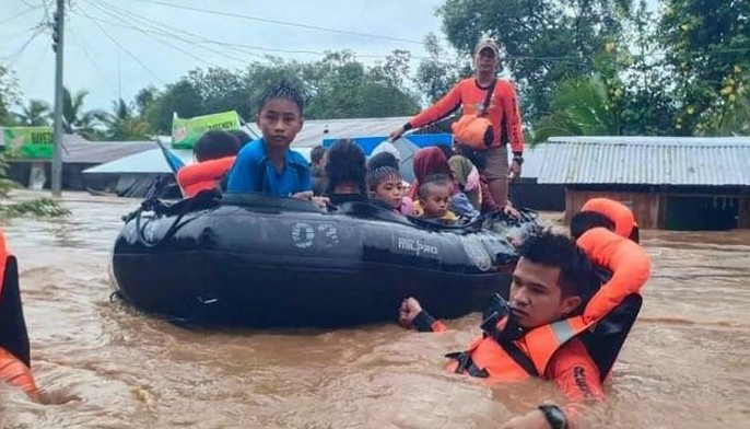 This handout photo taken and released by the Philippine Coast Guard on October 28, 2022 shows rescue workers evacuating people from a flooded area due to heavy rain brought by Tropical Storm Nalgae in Parang, Maguindanao province.