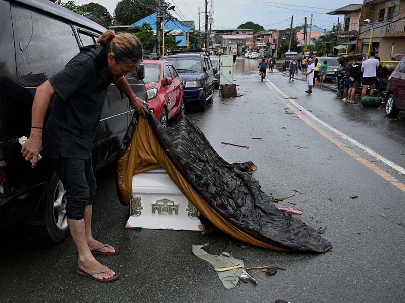 A man lifts the cover of a coffin that was swept away by flood due to heavy rains brought by Tropical Storm Nalgae in Kawit, Cavite province on October 30, 2022.