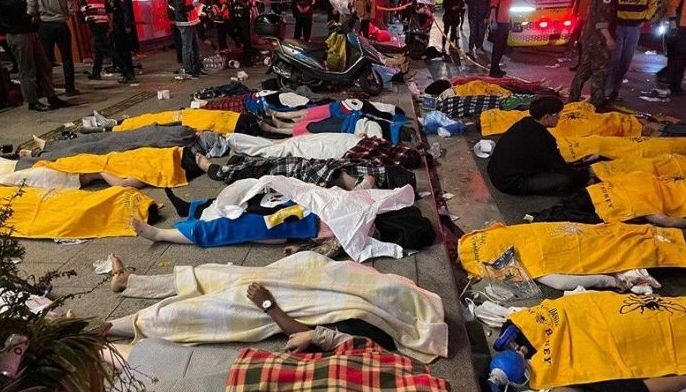 A man sits amid the bodies of victims, believed to have suffered cardiac arrest, in the popular nightlife district of Itaewon in Seoul on October 30, 2022. Dozens of people suffered from cardiac arrest in the South Korean capital Seoul, after thousands of people crowded into narrow streets in the city