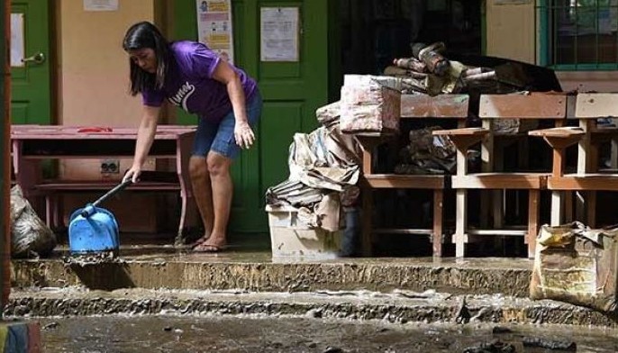 A teacher cleans her mud-filled classroom at a elementary school in Noveleta town, Cavite province, on October 31, 2022 after Tropical Storm Nalgae hit the region.
