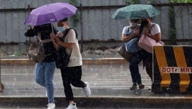 Commuters are seen seeking temporary cover from the rain at the Para&Atilde;&plusmn;aque Integrated Terminal Exchange on July 30, 2022.