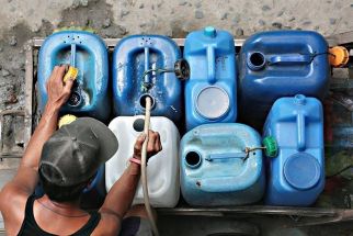 In this file photo from 2019, a man fills water containers from a neighbor&acirc;��s tap in Batasan, Quezon City ahead of a scheduled water interruption.