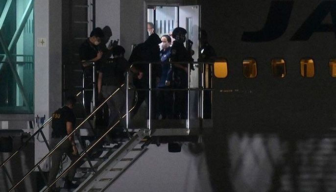 One of the two suspects (C wearing a hood), believed to be behind a spate of robberies in Japan, is escorted by authorities to a plane for deportation at the airport in Paranaque City, Metro Manila on February 8, 2023. 