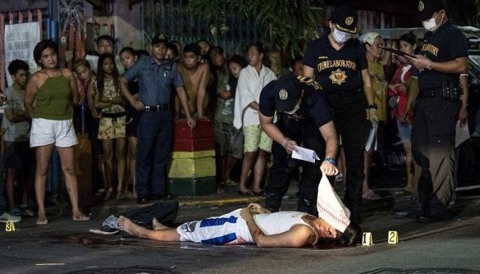 In this photograph taken on October 3, 2017, police personnel surround the body of an alleged drug user killed in Manila. Philippine police have shot dead 13 suspects in a drug crackdown, the government said March 22 after President Rodrigo Duterte defied allegations of crimes against humanity by announcing plans to take his country out of the International Criminal Court.