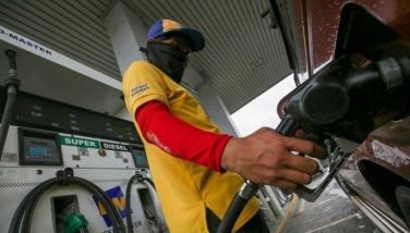 This photo shows a picture of a gasoline station staff filling a gas tank.