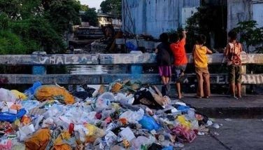 A pile of garbage, including plastic waste, is seen as children play on a bridge in downtown Manila on September 4, 2019.