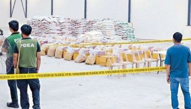 Agents guard 530 kilos of shabu concealed in Chinese tea packs, which were seized in a raid on a warehouse in Mexico, Pampanga yesterday. 