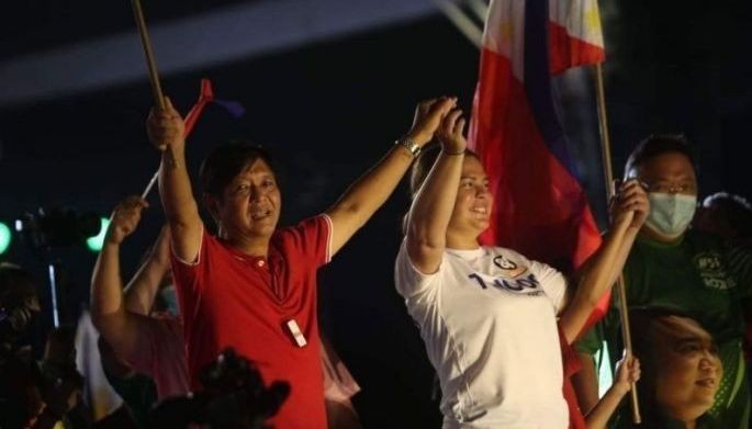 Bongbong Marcos Jr. and Sara Duterte, respectively as presidential and vice presidential aspirants, gesture before a massive crowd at the UniTeam campaign rally in Cebu City on April 18, 2022.