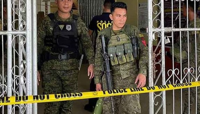 Military personnel stand guard at the entrance of a gymnasium while police investigators look for evidence after a bomb attack at Mindanao State University in Marawi, Lanao del sur province on December 3, 2023. 