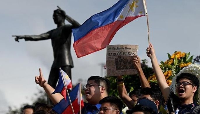 A supporter holds a copy of a newspaper from February 26, 1986 in front of the People Power Monument during the 38th anniversary of the &quot;People Power&quot; revolution, which ousted Philippine President Ferdinand Marcos Jr's dictator father and sent the family into exile, on Epifanio de los Santos Avenue, or EDSA, in Quezon City, metro Manila on February 25, 2024.