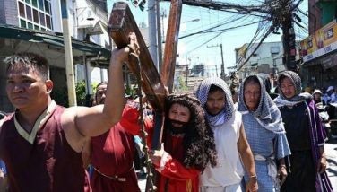 An actor playing the role of Jesus carries a wooden cross during the reenactment of the suffering and crucifixion of Jesus in a street play as part of Lenten observance during Holy Week in Manila on March 28, 2024, ahead of Easter.