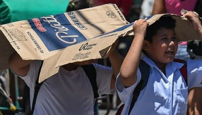 Students use a cardboard to protect themselves from the sun during a hot day in Manila on April 2, 2024. More than a hundred schools in the Philippine capital shut their classrooms on April 2, as the tropical heat hit &quot;danger&quot; levels, education officials said.