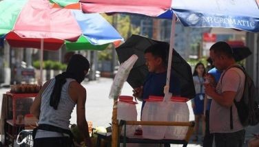 People buy coconut water to cool themselves along a road in Manila on April 24, 2024, as extreme heat affected the country.