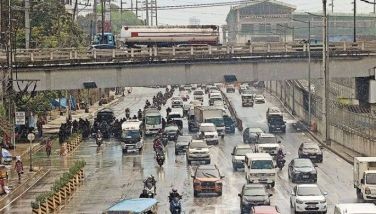 Motorists pass through rain puddles along Commonwealth Avenue in Quezon City following a sud- den downpour amid the scorching heat yesterday. 