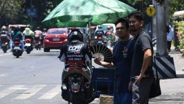 A pedestrian cools himself with a folding hand fan as he waits for a ride along a road in Manila on April 24, 2024, as extreme heat affected the country. Extreme heat scorched the Philippines on April 24, forcing schools in some areas to suspend in-person classes and prompting warnings for people to limit the amount of time spent outdoors. 