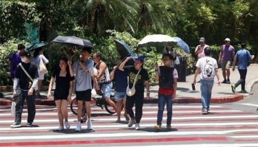 Pedestrians use different things, such as jackets, umbrellas, and small electric fans, to cope with the intense heat while crossing the street in Cubao, Quezon City on April 25, 2024.