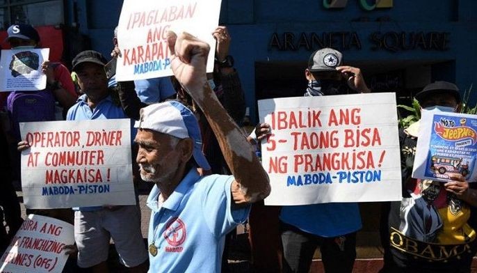 A jeepeney driver raises a clinched fist during a rally to coincide with their transport strike in Caloocan City, suburban Manila on March 6, 2023. Operators of traditional public jeepneys are holding a weeklong strike in various cities across the Philippines from March 6 to 12, 2023 to protest against the Public Utility Vehicle Modernization Program. 