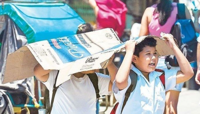 Students use a cardboard box to protect themselves from the sun during a hot day in Manila. More than a hundred schools nationwide have shut their classrooms and resorted to alternative learning modes due to sweltering temperatures, which have hit danger levels.
