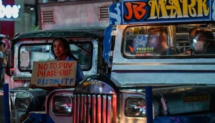 A man holds a placard as he joins a protest caravan to oppose the government&acirc;��s jeepney modernisation plan, in Manila on April 15, 2024. 