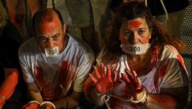 People sit with tape over their mouth and hands bound together during a rally calling for the release of Israelis held hostage in Gaza since the October 7 attacks by Palestinian Hamas militants, on the 200th day since their capture, outside Israel's Ministry of Defence in Tel Aviv on April 23, 2024.