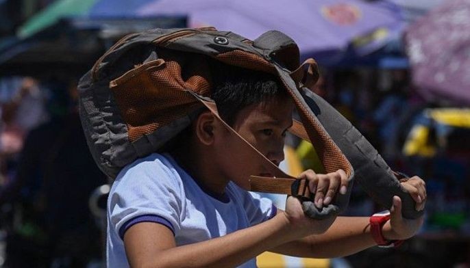 A student uses a bag to protect himself from the sun during a hot day in Manila on April 2, 2024. More than a hundred schools in the Philippine capital shut their classrooms on April 2, as the tropical heat hit &quot;danger&quot; levels, education officials said.