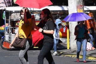 People walk with umbrellas during a heatwave in Manila on April 29, 2024.