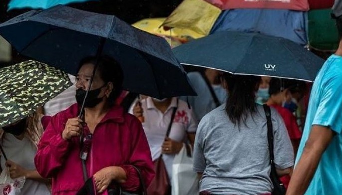 People walk along a street during rain in Manila on Sept. 10, 2022.