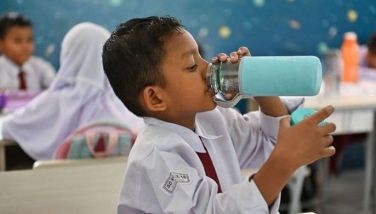 A primary school student has a drink in a classroom during hot weather in Banda Aceh on May 15, 2023. 