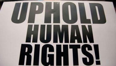 This file photo shows a protester holding a placard that says, &quot;Uphold human rights.&quot; 