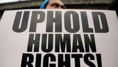 This file photo shows a protester holding a placard that says, &quot;Uphold human rights.&quot; 