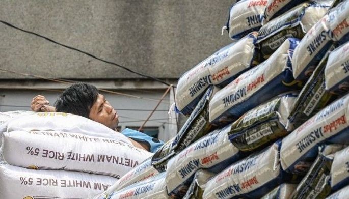 A man rests on sacks of rice along a street in Manila on May 9, 2024.