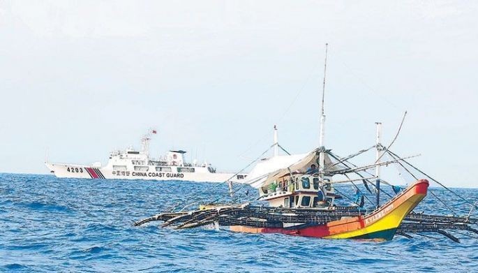 A China Coast Guard ship passes one of the boats of Atin Ito Coalition volunteers who decided not to sail closer to Panatag Shoal yesterday. Inset shows fishermen raising food packs they received from the civilian resupply mission. 